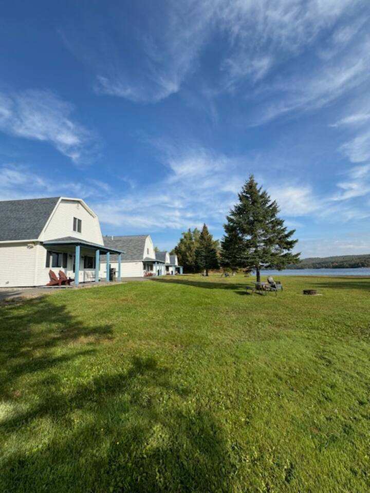 All five cottages at Eagles Landing seen across the lawn, gambrel roofs and covered porches facing Eagle Lake.