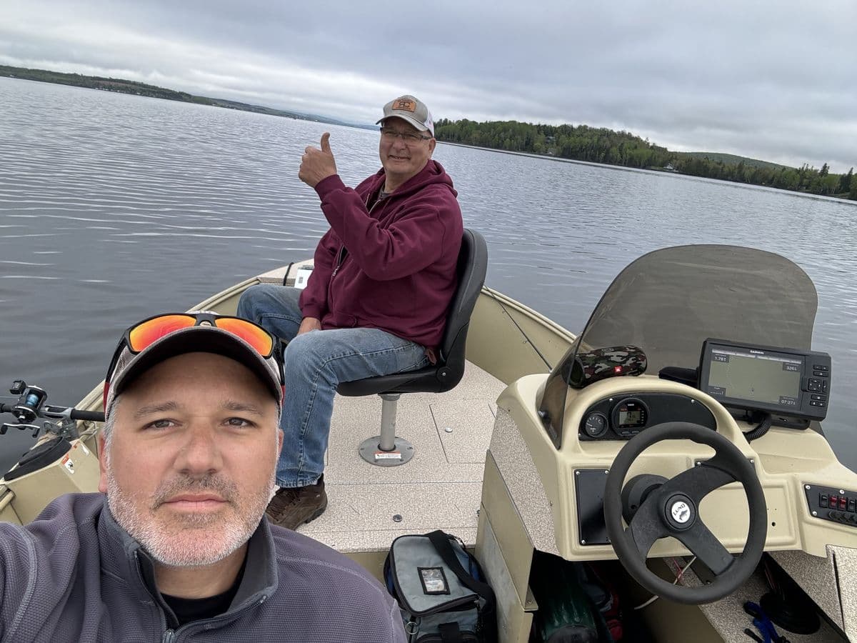 Matt Rode and a fishing partner in an aluminum fishing boat on Eagle Lake on an overcast morning, rods rigged, one giving a thumbs up.