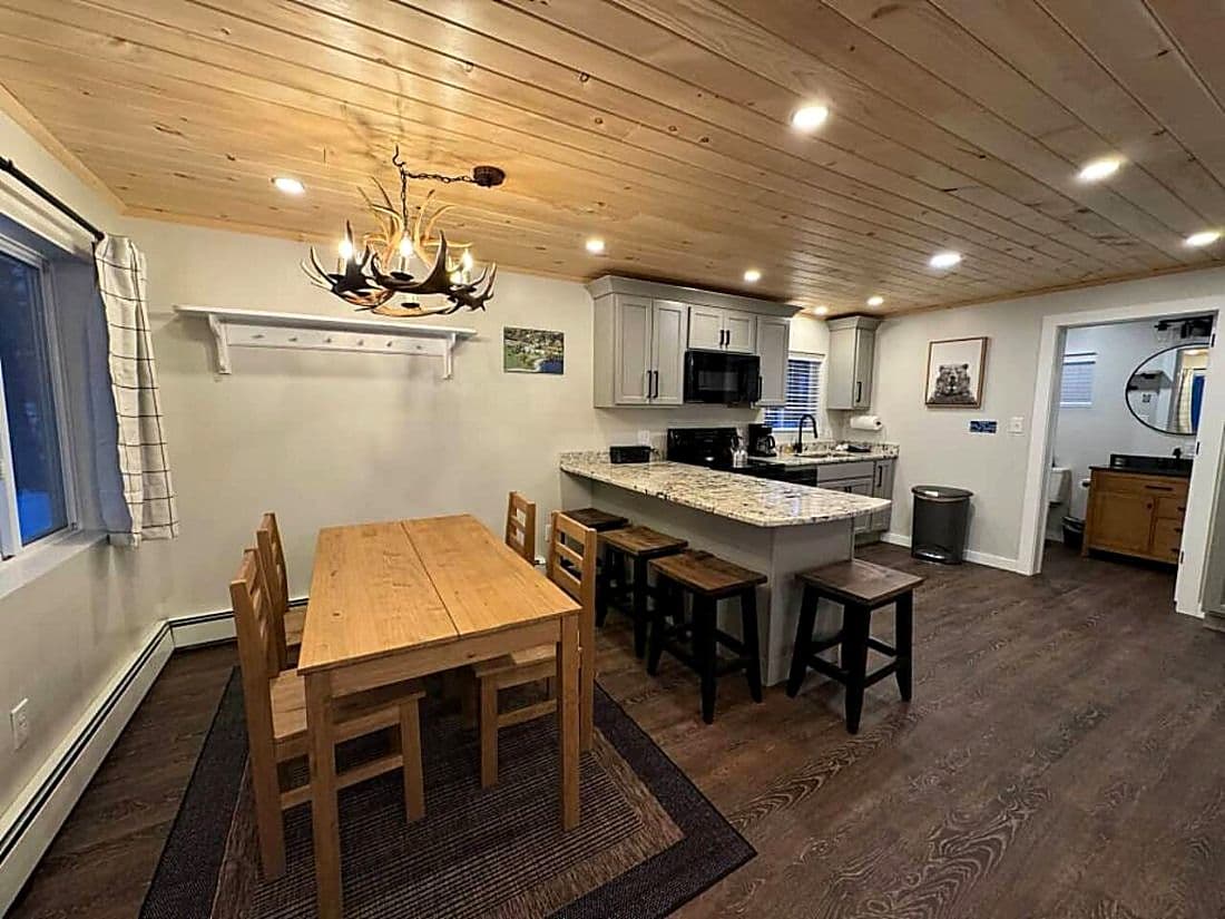 A cottage kitchen with a granite counter, bar stools and the dining table.