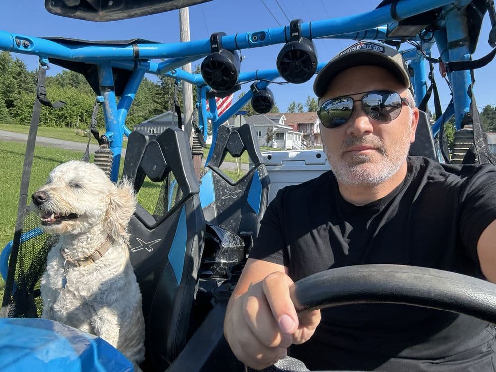Matt Rode at the wheel of a blue side-by-side with a white doodle in the passenger seat.