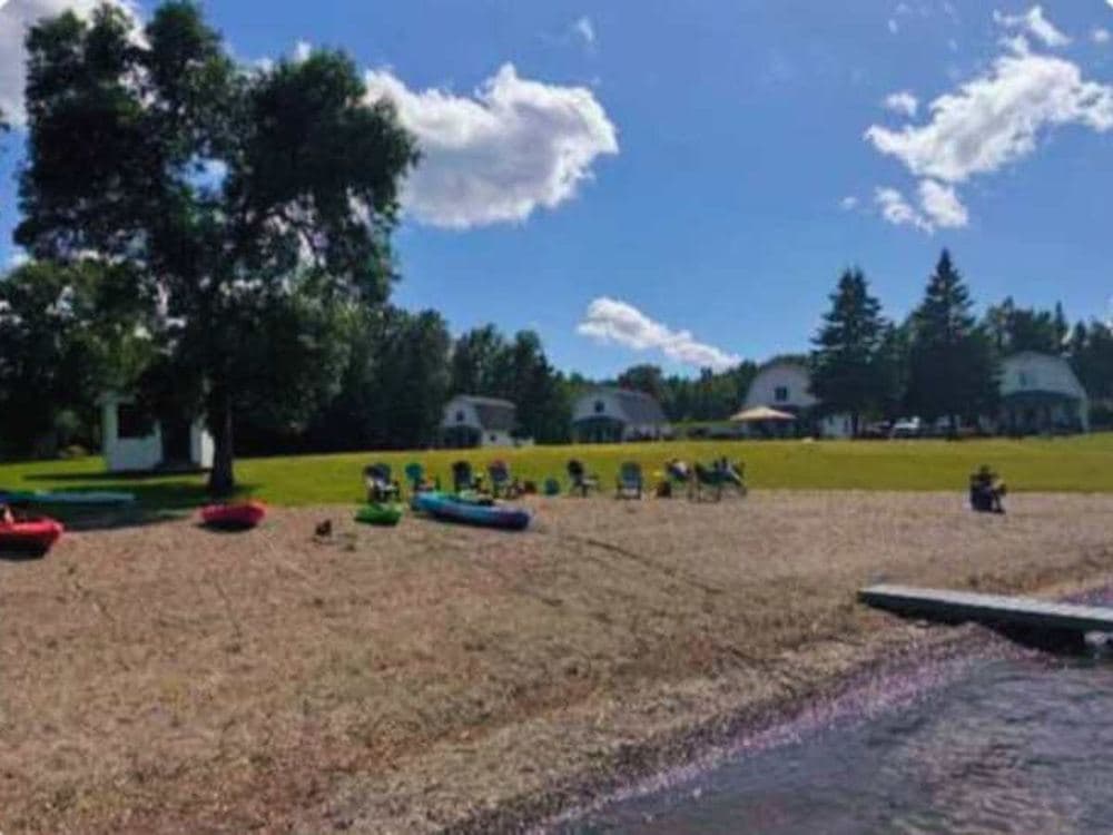 The beach with kayaks and lawn chairs on the sand, and the cottages behind it.